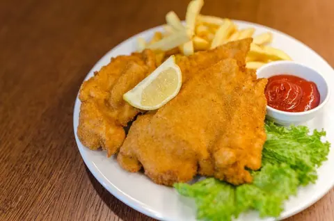 Paniertes Schnitzel mit Zitrone, Pommes und Salat
