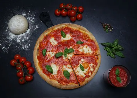 Pizza mit Tomatensauce, Mozzarella und Basilikum auf dunklem Untergrund