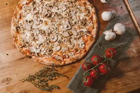 Pizza mit Champignons auf einem Holzbrett