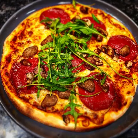 Pizza mit Salami, Champignons und Rucola