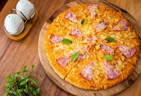 Pizza mit Schinken und Mozzarella auf einem Holzbrett