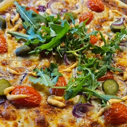 Pizza mit Gewürzgurken, Kirschtomaten, Zwiebeln und Burgersauce