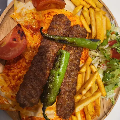 Zwei Hackfleischspieße mit Pommes und gegrillter Peperoni