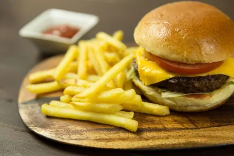 Cheeseburger mit Pommes auf einem Holzbrett