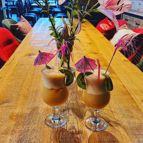 Zwei Cocktails mit Schirmchen auf einem Holztisch