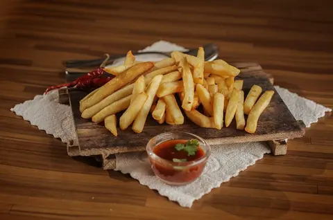 Pommes frites auf einem Holzbrett mit Dip