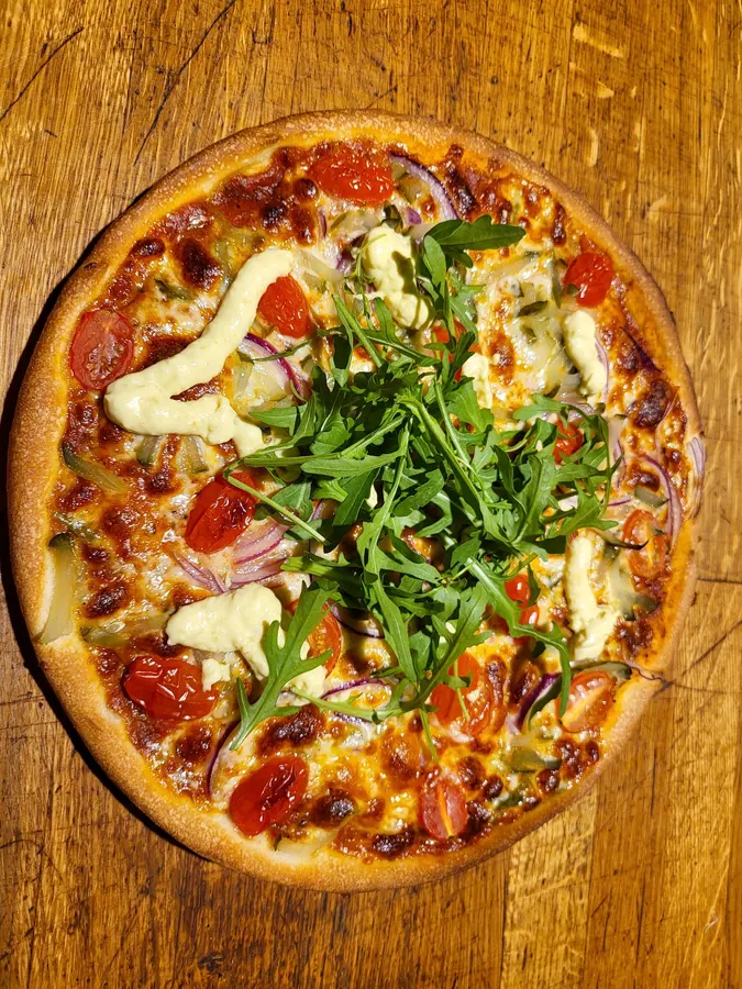 Pizza mit Rucola auf dem Holzbrett